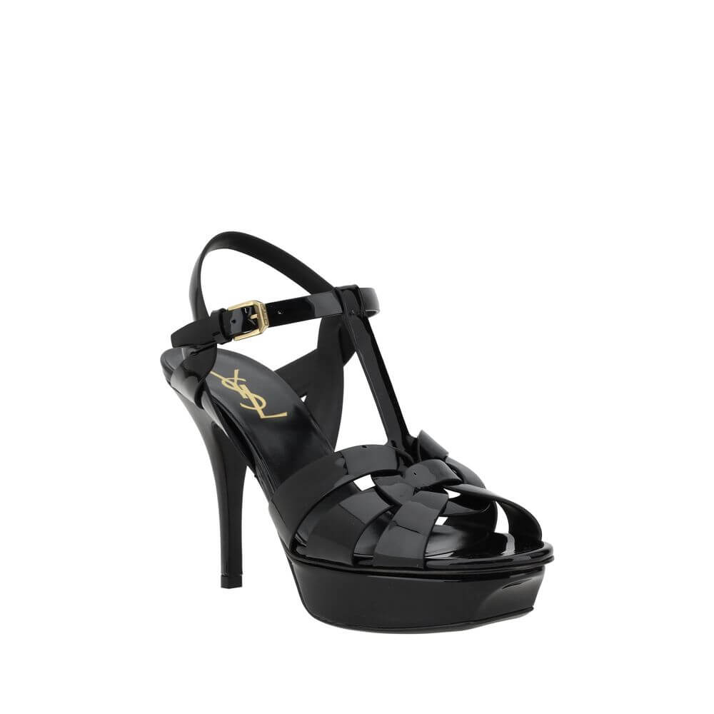 Tribute SandalsSaint Laurent’s Tribute Sandals are a timeless classic that combines elegance and boldness. Featuring a caged design on the upper, these sandals offer a sophisticated and sensual silhouette, enhanced by a patent leather finish that lends a