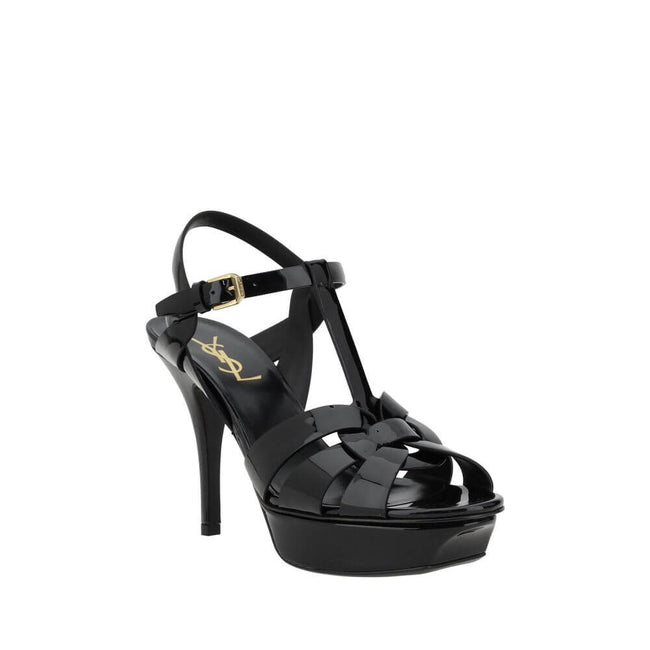 Tribute SandalsSaint Laurent’s Tribute Sandals are a timeless classic that combines elegance and boldness. Featuring a caged design on the upper, these sandals offer a sophisticated and sensual silhouette, enhanced by a patent leather finish that lends a