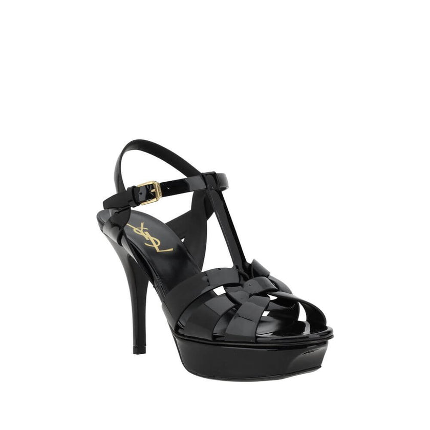 Tribute SandalsSaint Laurent’s Tribute Sandals are a timeless classic that combines elegance and boldness. Featuring a caged design on the upper, these sandals offer a sophisticated and sensual silhouette, enhanced by a patent leather finish that lends a