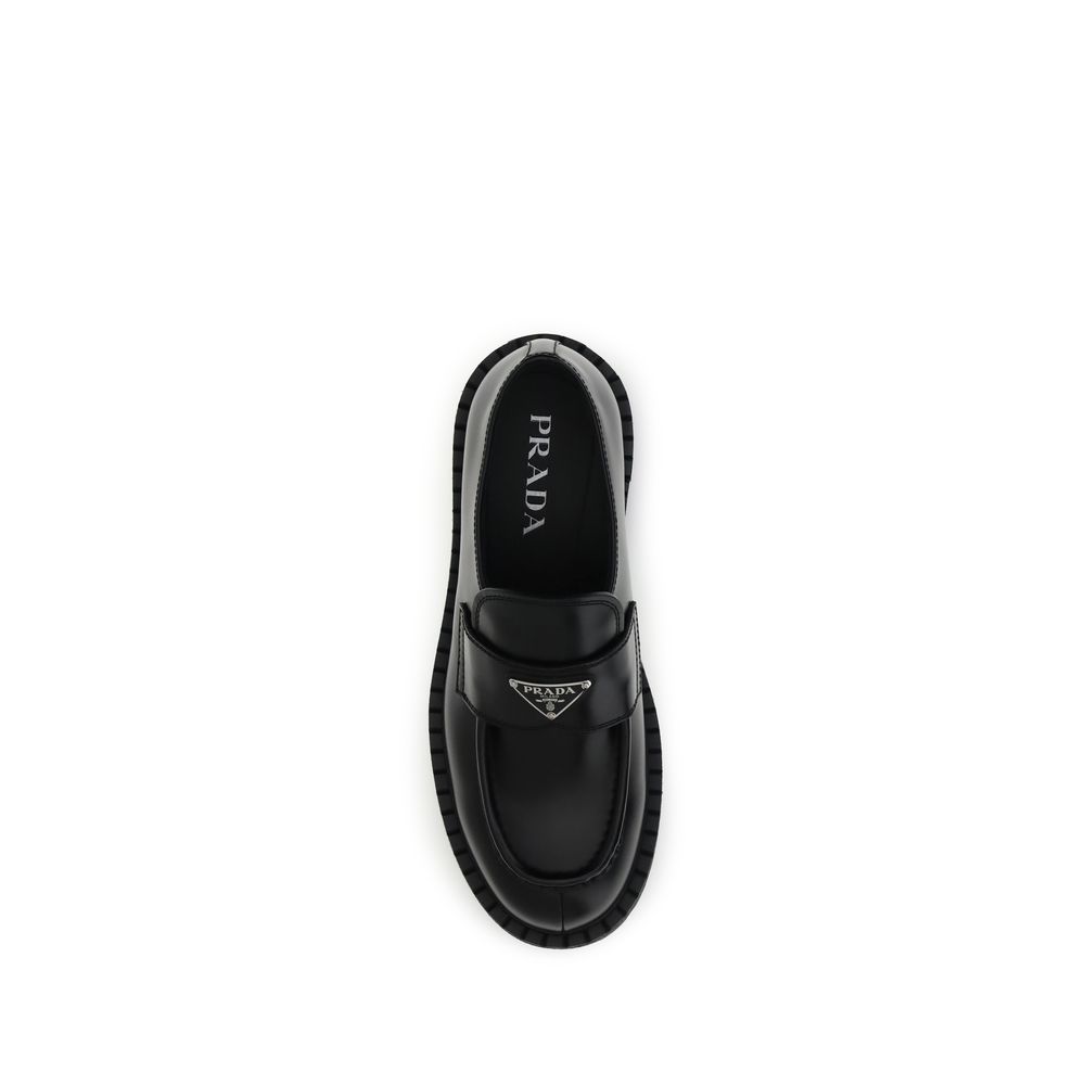 Black Calf Leather Bos Taurus Slip-On LoafersPrada’s leather Double Chocolate Loafers feature a band decorated with an enameled metal triangle, the brand’s distinctive symbol. They feature a stitched tray with burlotto and a volumetric rubber sole with do