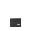 Black Leather WalletFerragamo’s Gancini Card Holder is a compact and elegant accessory with five internal compartments for cards and one dedicated to coins. The red interior gives a lively and refined touch, while the Gancini logo on the front signs the d