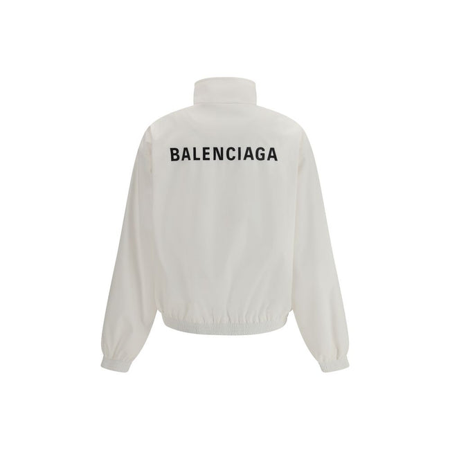 White Polyester Shell JacketBalenciaga’s Windbreaker Jacket is made of technical fabric and features contrasting logo embroidery on the chest and back. Featuring a high collar and concealed zipper closure, it offers two front zipper pockets. Gathered elas