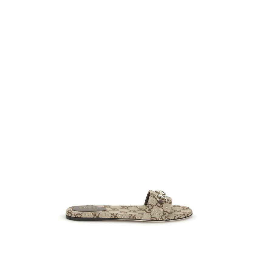 GG canvas SlippersThese Gucci GG canvas Slippers combine elegance and recognizability thanks to the brand’s iconic motif. Embellished with a refined metal horsebit detail on the instep, they feature a round toe for a classic touch. The logo label on the i