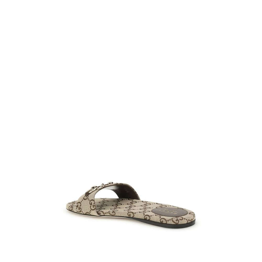 GG canvas SlippersThese Gucci GG canvas Slippers combine elegance and recognizability thanks to the brand’s iconic motif. Embellished with a refined metal horsebit detail on the instep, they feature a round toe for a classic touch. The logo label on the i