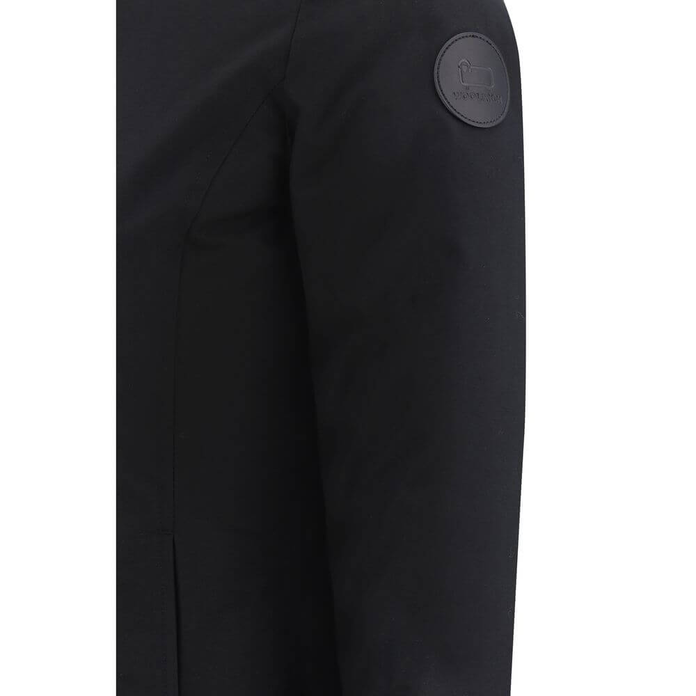 Black Nylon ParkaBoulder Down Jacket by Woolrich, front zipper closure with concealed snap buttons, faux fur-lined hood design, elastic ribbed cuffs, padded and quilted inner lining design, buttoned welt pockets, brand’s iconic logo patch applied on left