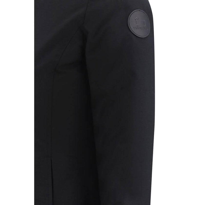 Black Nylon ParkaBoulder Down Jacket by Woolrich, front zipper closure with concealed snap buttons, faux fur-lined hood design, elastic ribbed cuffs, padded and quilted inner lining design, buttoned welt pockets, brand’s iconic logo patch applied on left