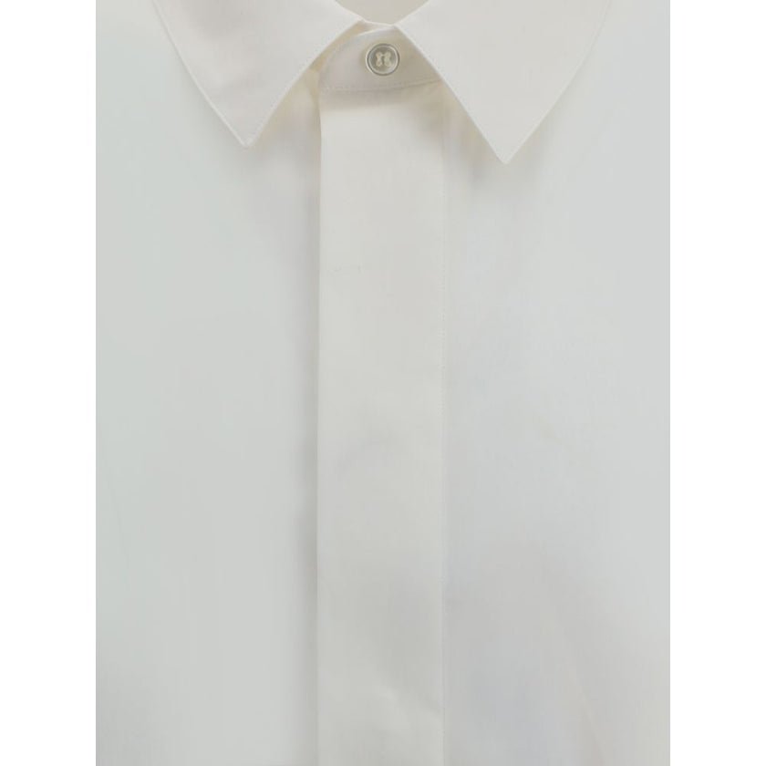 White Cotton Dress ShirtSaint Laurent’s cotton Shirt is a clean and elegant design. Made of cotton poplin, it features a classic collar, a front closure with concealed buttons for a minimal and neat effect, and a discreet but distinctive embroidered logo