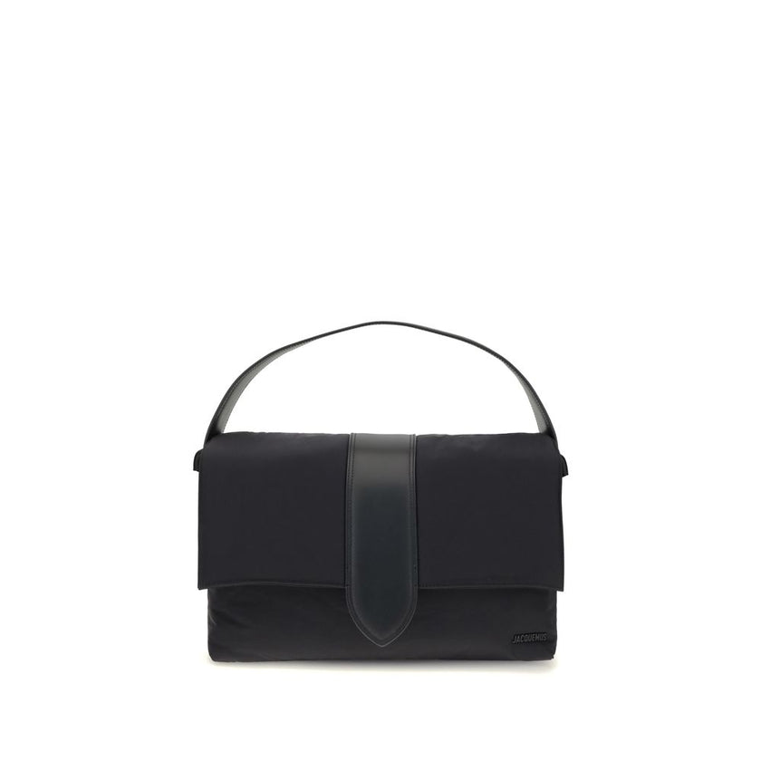 Black Nylon Shoulder BagThe Bambino Shoulder Bag by Jacquemus reinterprets the messenger style with a practical, contemporary design. Made of padded nylon, it features a leather handle and magnetic flap with tab, combined with a zipper closure for added s