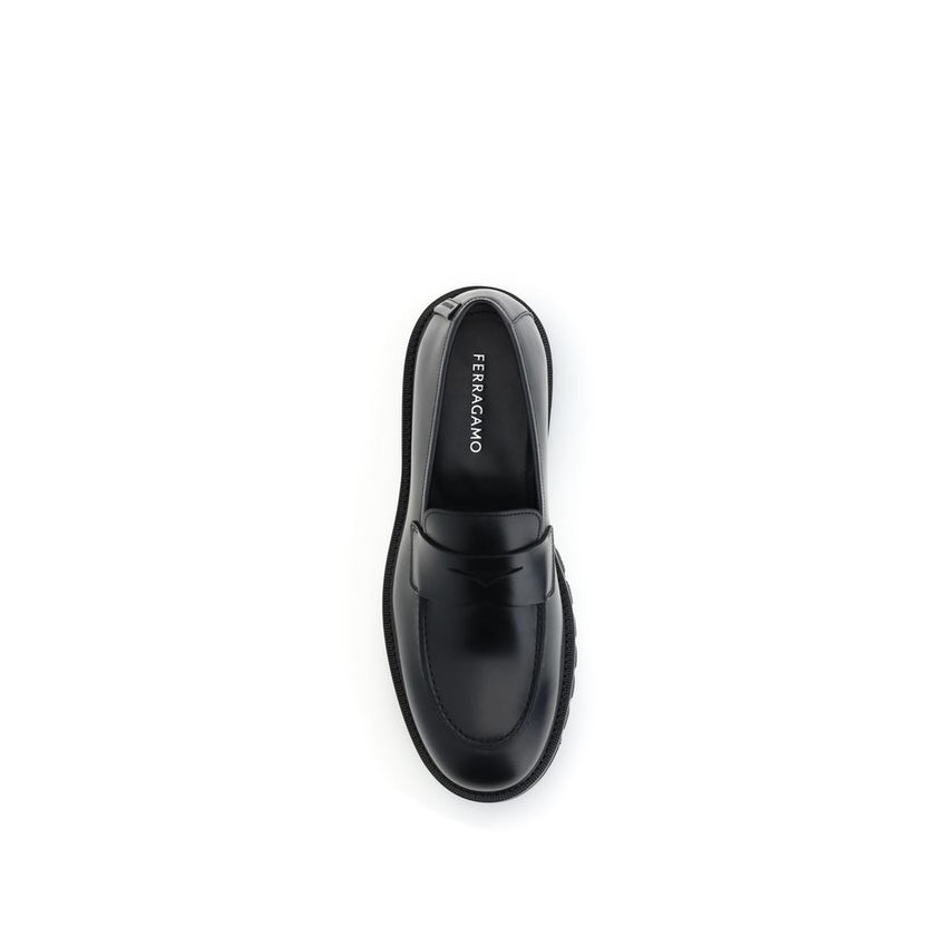 Black Rubber Slip-On LoafersFerragamo’s Penny Loafers reinterpret a classic with a contemporary twist. Featuring a slightly rounded toe and a brushed calfskin upper, they offer the perfect balance of elegance and comfort. Iconic details, such as the conto