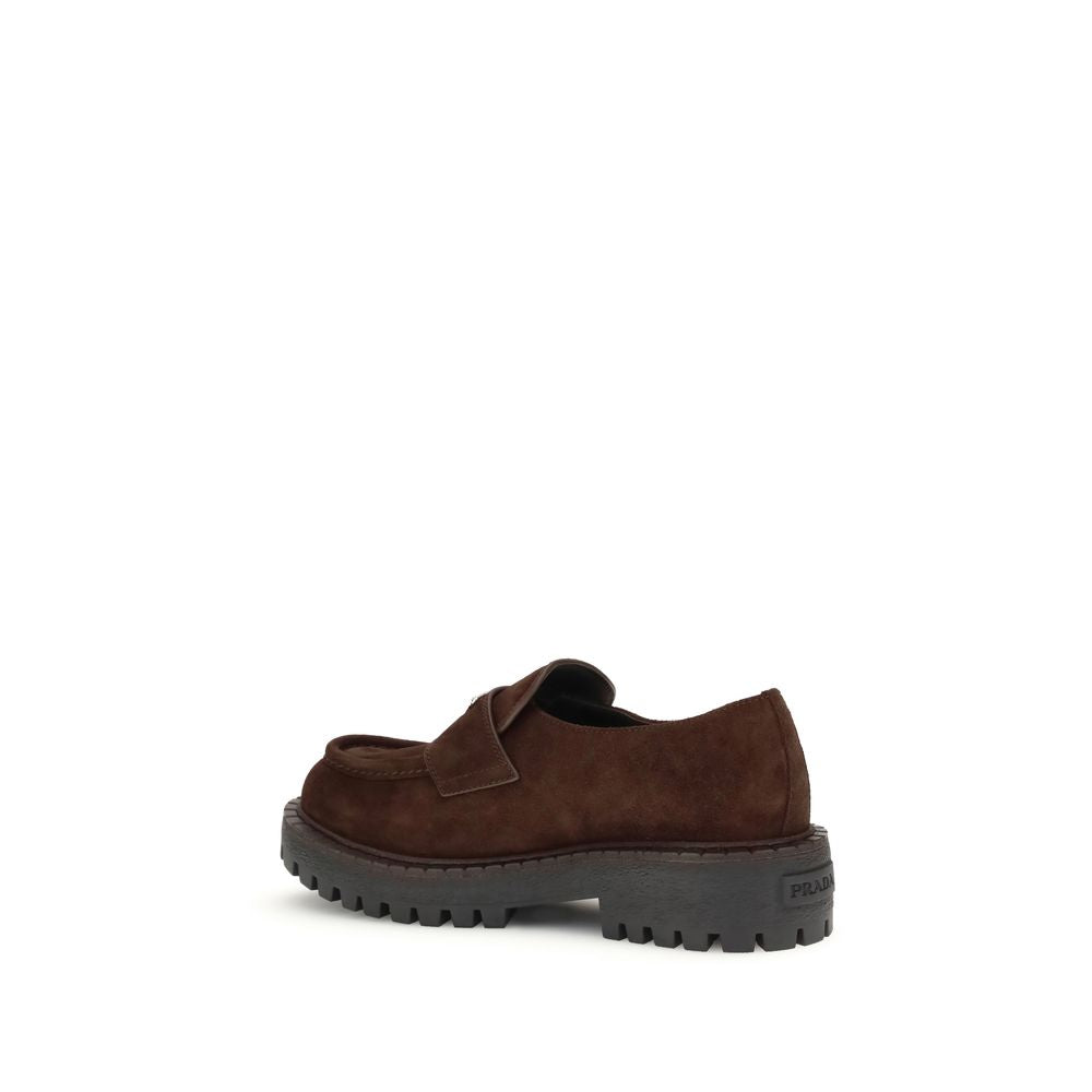 Brown Calf Leather Bos Taurus Slip-On LoafersPrada’s Suede Loafers combine classic elegance with iconic details. Characterized by the enameled metal triangle logo on the front, they feature a one-piece rubber sole with a branded logo, ensuring comfort and
