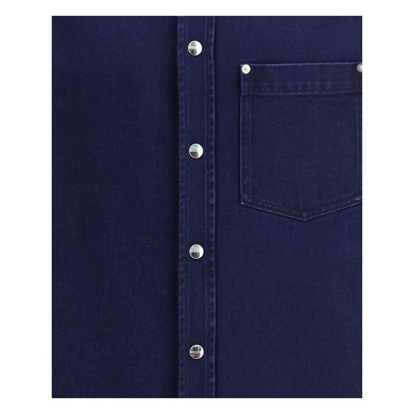 Blue Denim ShirtGucci’s reversible Shirt combines dark blue délavé denim on one side and soft red and blue brushed GG flannel on the other. Featuring a pointed collar, chest pocket, side pockets and long sleeves, it has a front closure with Gucci metal bu