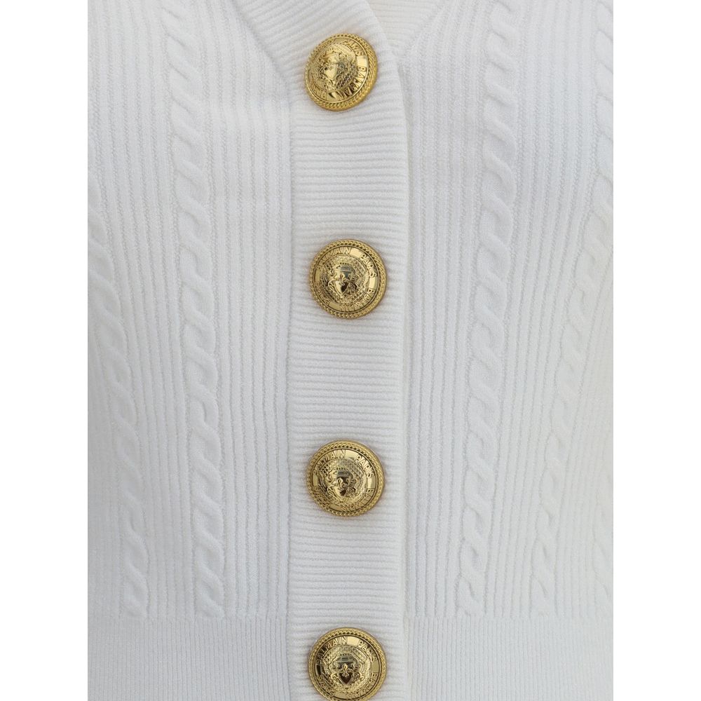 Ribbed and braided CardiganBalmain’s Ribbed and braided Cardigan combines elegance and structure in a distinctive design. Featuring a V-neckline, it features structured shoulders with decorative tabs and buttons, recalling the military aesthetic dear to t