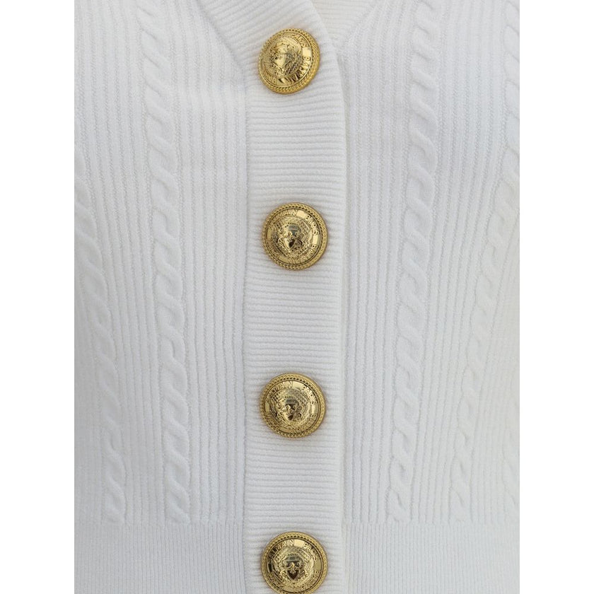 Ribbed and braided CardiganBalmain’s Ribbed and braided Cardigan combines elegance and structure in a distinctive design. Featuring a V-neckline, it features structured shoulders with decorative tabs and buttons, recalling the military aesthetic dear to t