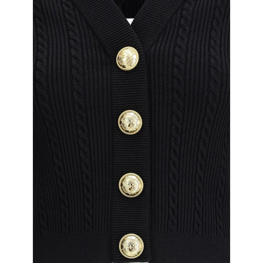 Black Viscose CardiganBalmain’s Ribbed and braided Cardigan combines elegance and structure in a distinctive design. Featuring a V-neckline, it features structured shoulders with decorative tabs and buttons, recalling the military aesthetic dear to the Ma
