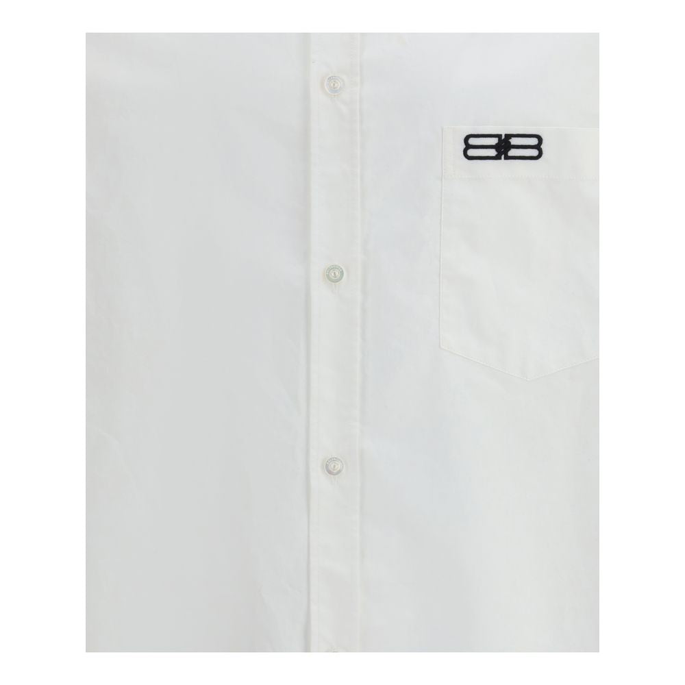 White Cotton Dress ShirtBalenciaga’s oversized cotton Shirt features a contemporary and striking design. It features a front button closure, a classic collar and an asymmetrical hem that adds dynamism to the silhouette. A small patch pocket on the front,