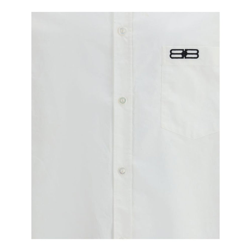 White Cotton Dress ShirtBalenciaga’s oversized cotton Shirt features a contemporary and striking design. It features a front button closure, a classic collar and an asymmetrical hem that adds dynamism to the silhouette. A small patch pocket on the front,