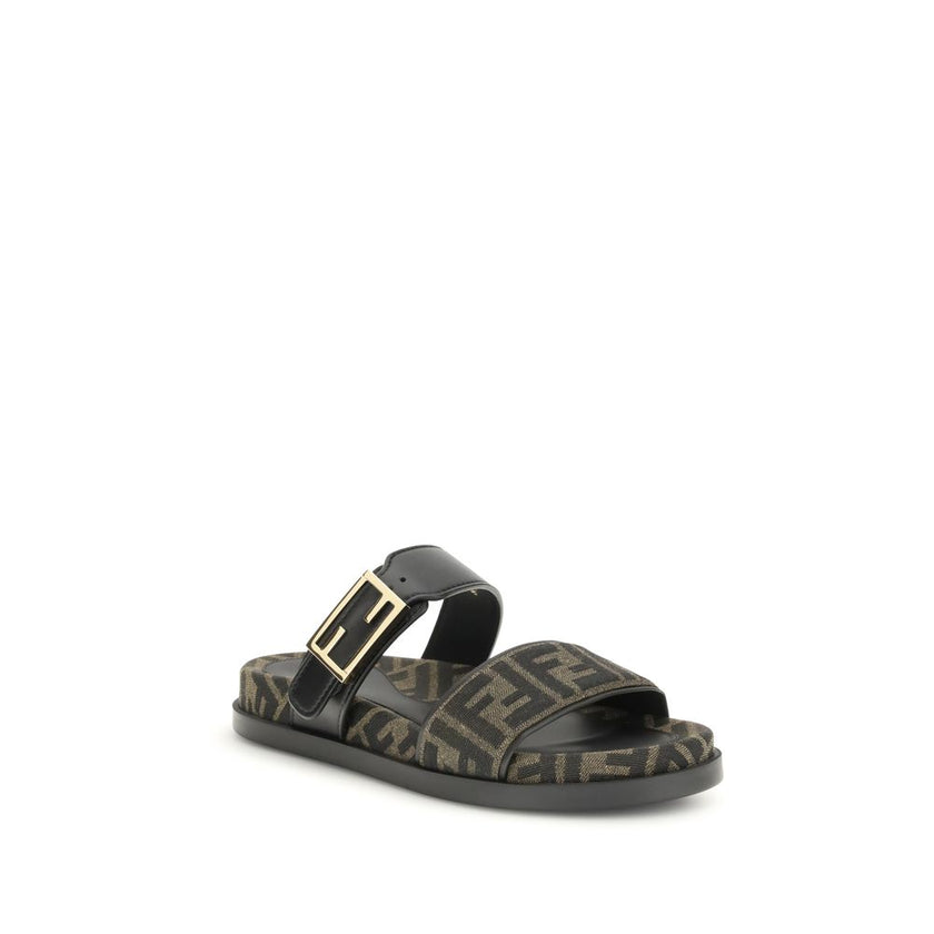 FF fabric sandalThe FF fabric Sandal by Fendi is a flat slide featuring a double strap with a decorative FF Baguette buckle. Crafted in jacquard fabric with the iconic FF pattern and black nappa leather details, it is finished with gold-tone metal hardwar