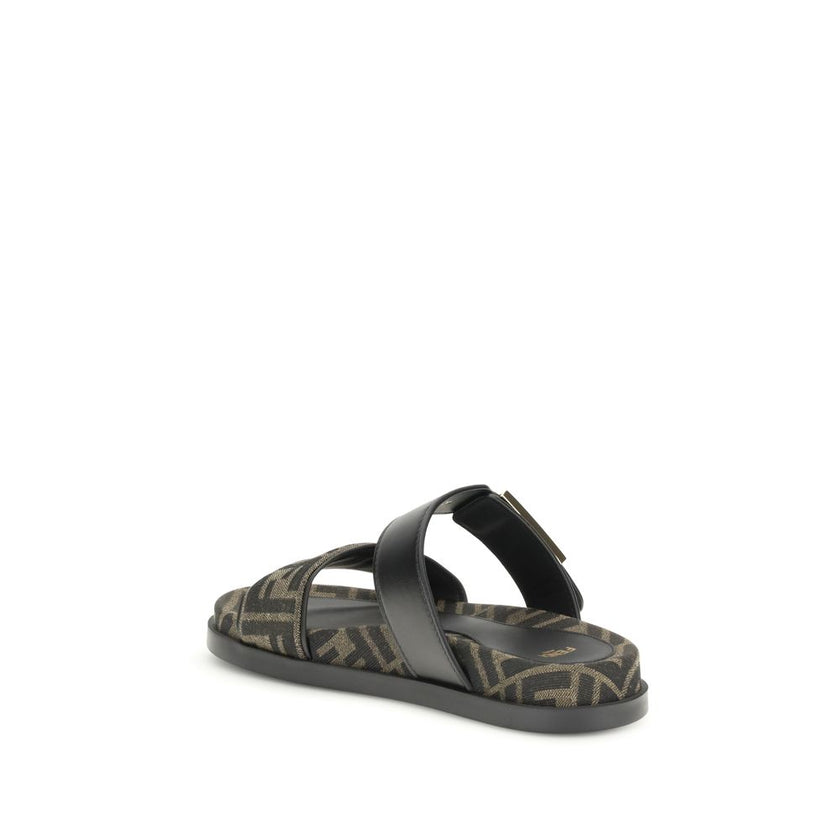 FF fabric sandalThe FF fabric Sandal by Fendi is a flat slide featuring a double strap with a decorative FF Baguette buckle. Crafted in jacquard fabric with the iconic FF pattern and black nappa leather details, it is finished with gold-tone metal hardwar