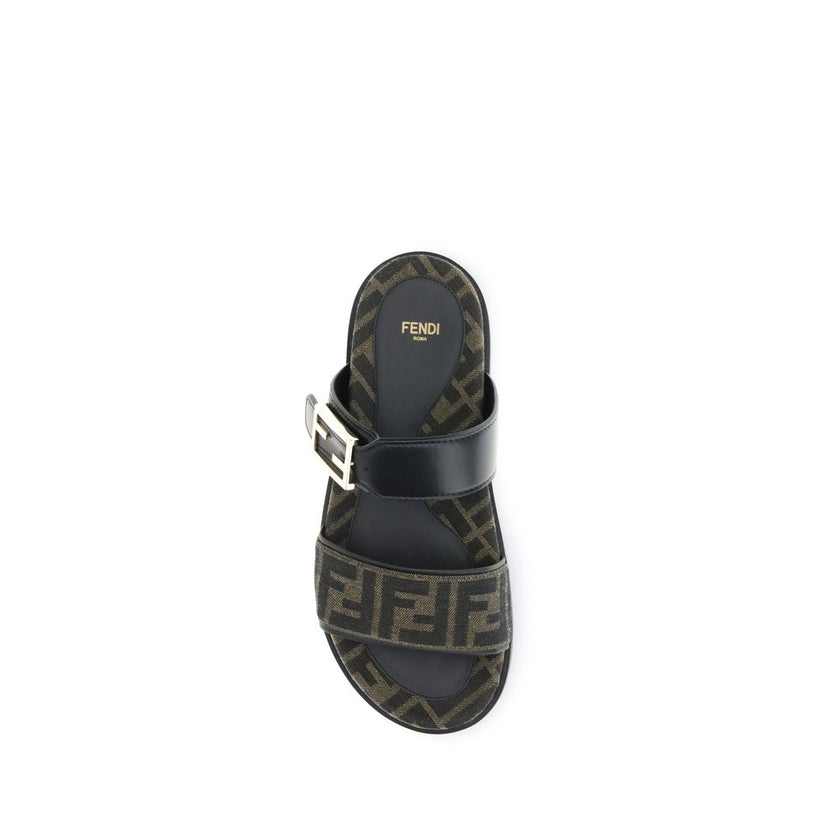 FF fabric sandalThe FF fabric Sandal by Fendi is a flat slide featuring a double strap with a decorative FF Baguette buckle. Crafted in jacquard fabric with the iconic FF pattern and black nappa leather details, it is finished with gold-tone metal hardwar