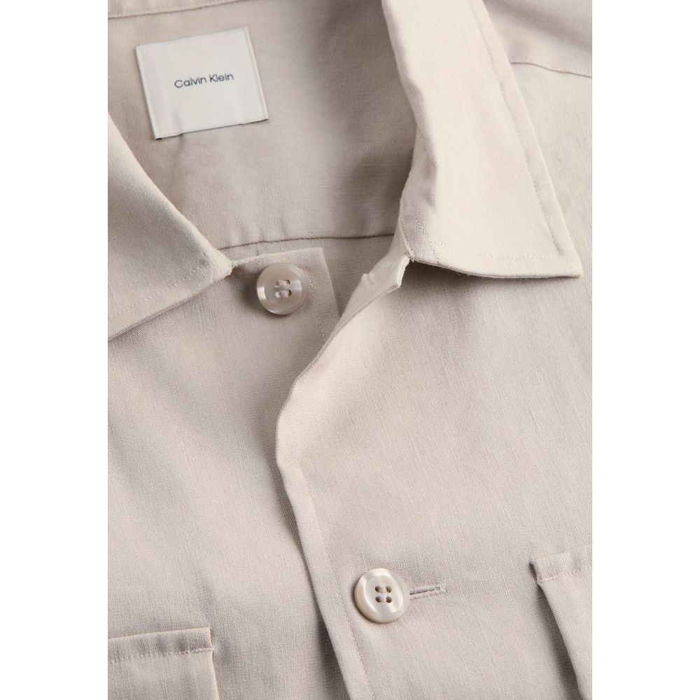 Beige Lyocell ShirtDiscover the long-sleeve men’s shirt by Calvin Klein, a clothing piece that combines elegance and practicality. Made from a refined blend of 51% Lyocell, 47% Linen, and 2% Elastane, this shirt offers exceptional comfort and a perfect fi