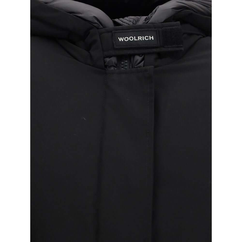 Black Cotton ParkaArctic parka Jacket by Woolrich is made of durable Ramar Cloth fabric, treated with Teflon coating to provide protection from water and wind. Featuring a front zipper and concealed button closure, it has a protective hood, Velcro closure
