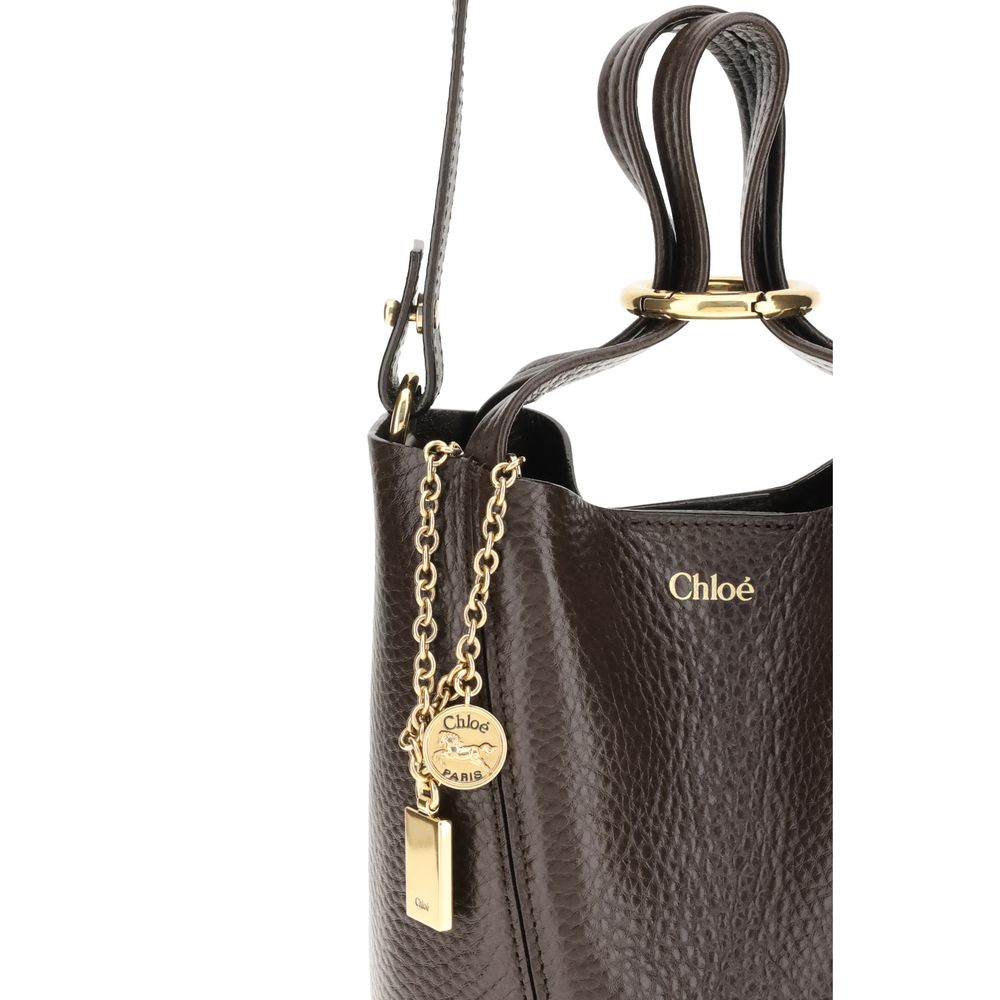 Spin Shoulder BagThe Spin Shoulder Bag by Chloé, crafted by shiny grained leather, features an elegant design with two flat top handles and an adjustable shoulder strap. The closure is secured by a magnetic button, while the detail of the hanging chain wi