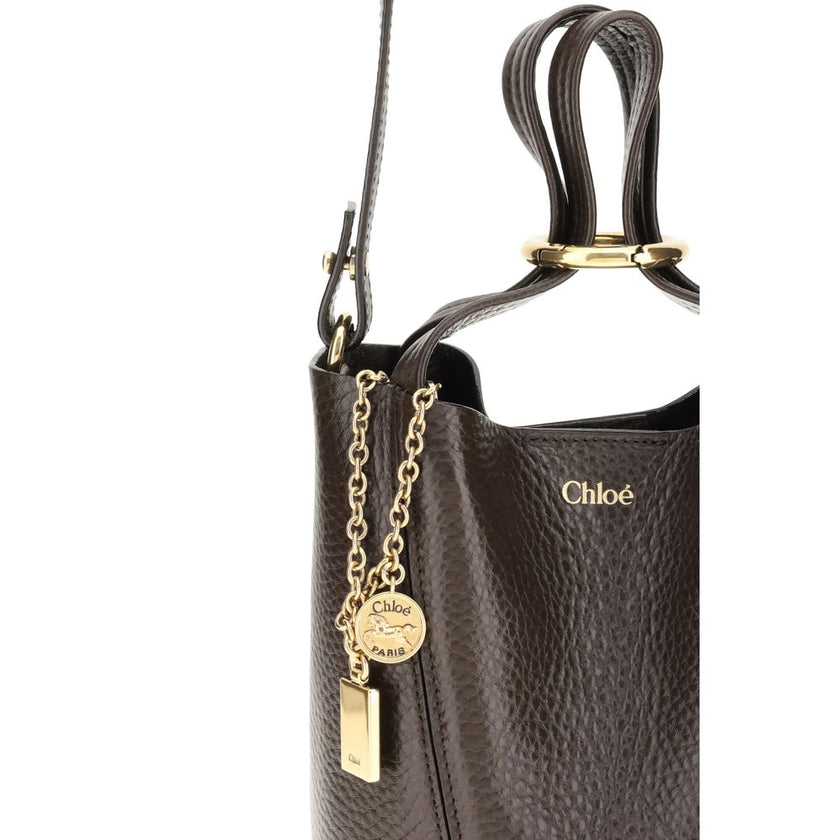 Spin Shoulder BagThe Spin Shoulder Bag by Chloé, crafted by shiny grained leather, features an elegant design with two flat top handles and an adjustable shoulder strap. The closure is secured by a magnetic button, while the detail of the hanging chain wi
