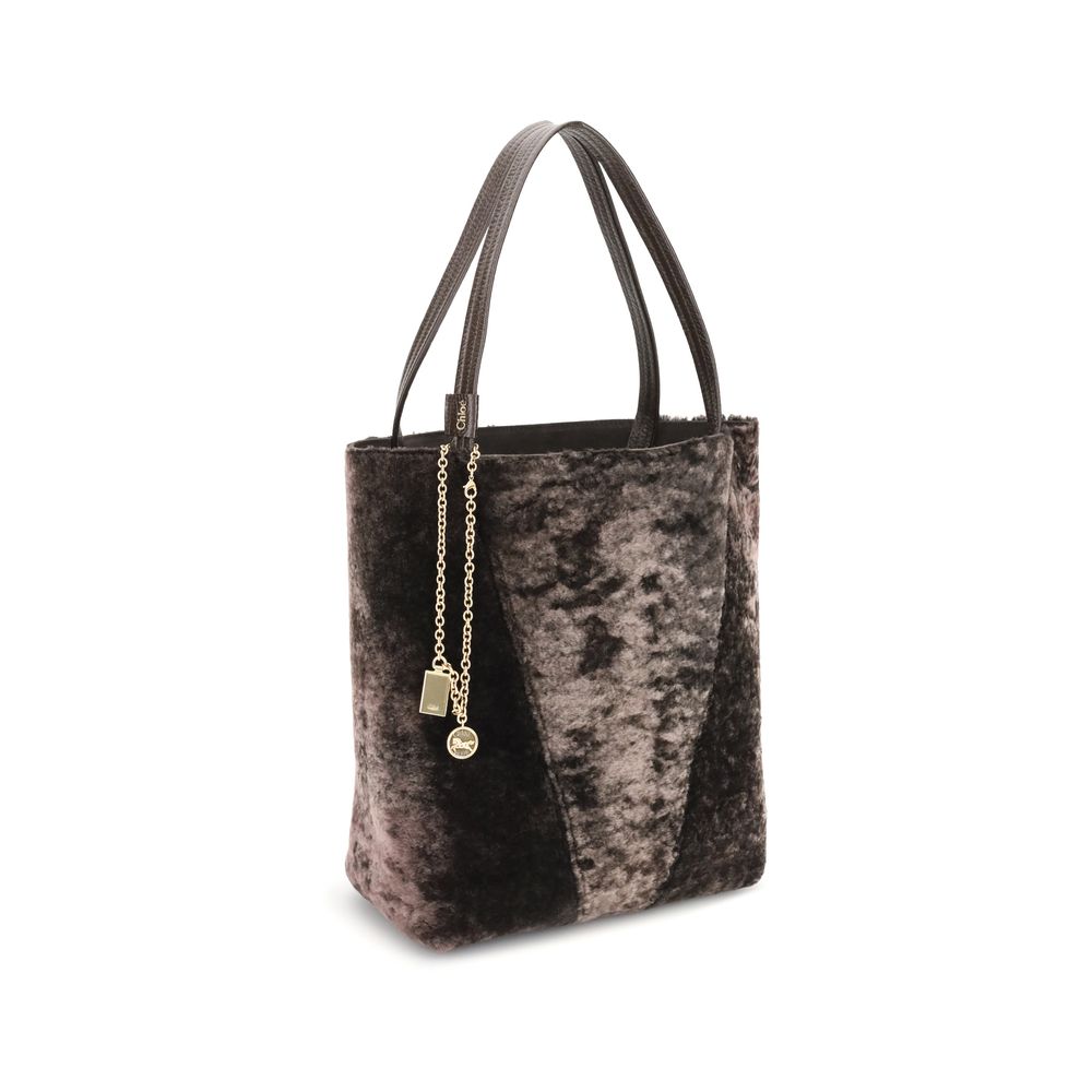 Brown Lamb Ovis Aries Aries Shoulder BagThe Spin Shearling Tote Bag by Chloé is a dark brown shearling tote accented with gold-tone hardware. It features double handles and a decorative chain with Chloé and Horse pendants. The tone-on-tone interior comple