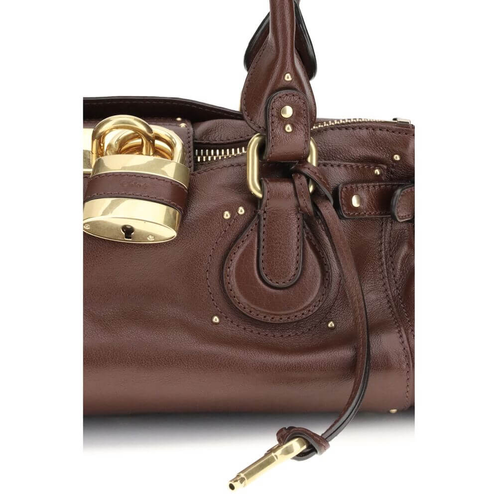 Bordeaux Buffalo Leather Shoulder BagThe Paddington Bag in garnet leather by Chloé is crafted from buffalo leather with suede leather details. Equipped with an aluminum lock, it can be carried by hand or over the shoulder. It features a main compartment,