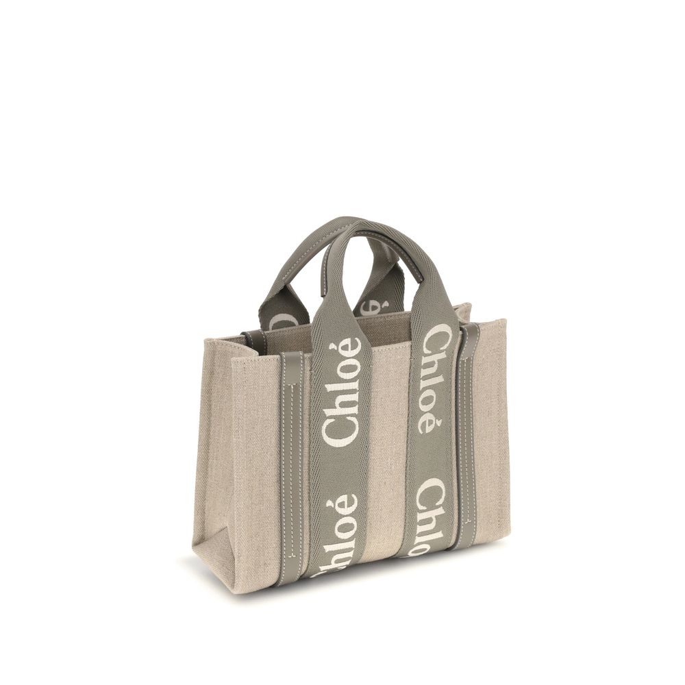 Beige Linen HandbagChloé’s Woody Handbag is an elegant and practical accessory made of linen and detailed with contrasting leather. The concealed button top closure maintains a clean design, while the double flat handles and extension on the leather side