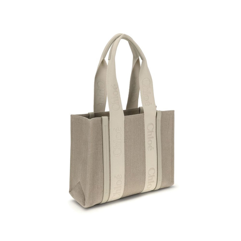 Beige Linen Shoulder BagChloé’s Woody Shoulder Bag by Chloé is crafted from elegant linen with a refined design and distinctive details. Double flat handles are enhanced by contrasting leather extensions on the side panels, while the brand’s iconic monogr