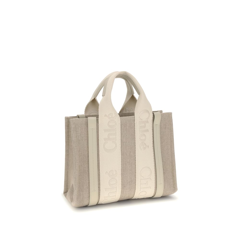 Beige Linen HandbagChloé’s Woody Handbag is an elegant and practical accessory made of linen and detailed with contrasting leather. The concealed button top closure maintains a clean design, while the double flat handles and extension on the leather side