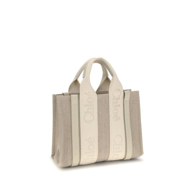 Beige Linen HandbagChloé’s Woody Handbag is an elegant and practical accessory made of linen and detailed with contrasting leather. The concealed button top closure maintains a clean design, while the double flat handles and extension on the leather side