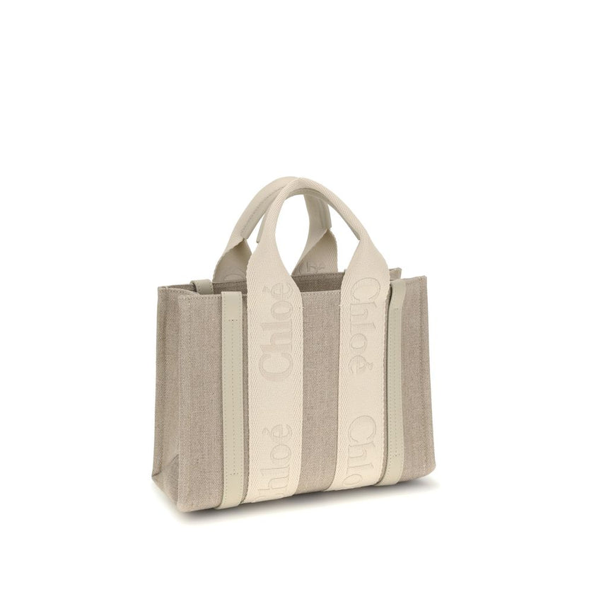 Beige Linen HandbagChloé’s Woody Handbag is an elegant and practical accessory made of linen and detailed with contrasting leather. The concealed button top closure maintains a clean design, while the double flat handles and extension on the leather side