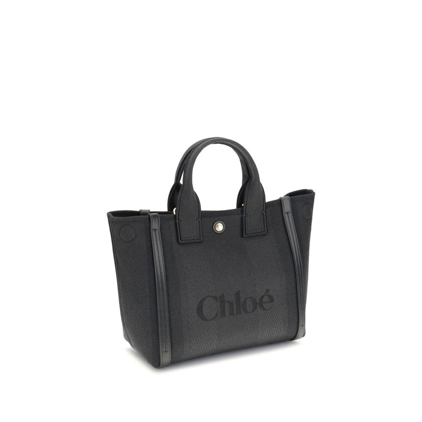 Black Cotton Shoulder BagChloé’s Carry Tote Bag is a stylish, multifunctional accessory made of cotton with contrasting leather details that accentuate its sophisticated appeal. Magnetic buttons on the side panels allow you to adjust the width of the bag