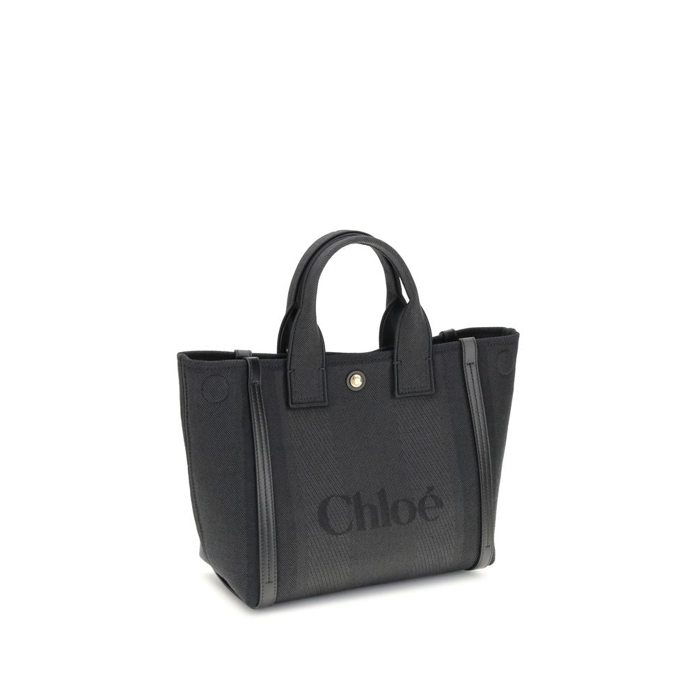 Black Cotton Shoulder BagChloé’s Carry Tote Bag is a stylish, multifunctional accessory made of cotton with contrasting leather details that accentuate its sophisticated appeal. Magnetic buttons on the side panels allow you to adjust the width of the bag