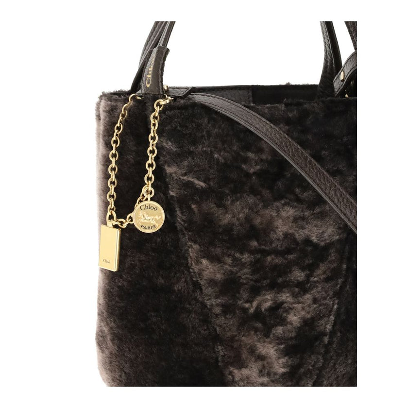 Brown Fur Shoulder BagSpin small Tote Bag by Chloè in soft shearling is distinguished by a compact, minimalist silhouette defined by clean graphic lines. The discreet elegance of the design is enhanced by a dangling chain with the iconic Chloé medals and