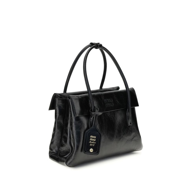 Black Calf Leather Bos Taurus HandbagSolitaire Handbag by Miu Miu combines structured lines and refined details, inspired by the maison’s 2006 archives. Made of shiny calfskin, it blends classic elegance and contemporary spirit, enhanced by the front leat