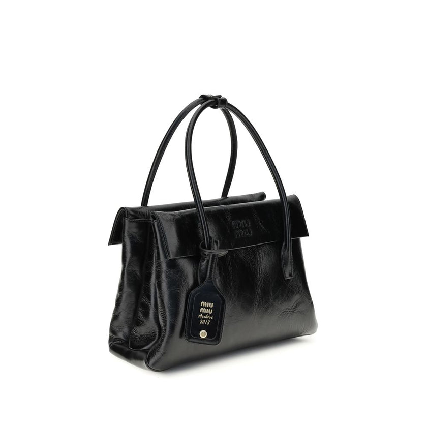 Black Calf Leather Bos Taurus HandbagSolitaire Handbag by Miu Miu combines structured lines and refined details, inspired by the maison’s 2006 archives. Made of shiny calfskin, it blends classic elegance and contemporary spirit, enhanced by the front leat