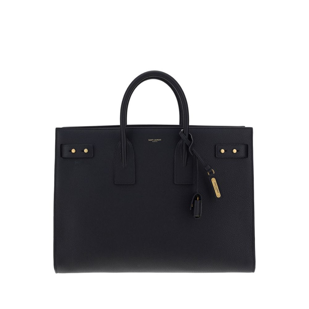 Black Calf Leather Bos Taurus HandbagThe Sac De Jour bag by Saint Laurent combines functionality and style with a soft structure, side gussets, and compression straps with tabs. It features round handles with a lock housed in a removable leather case and