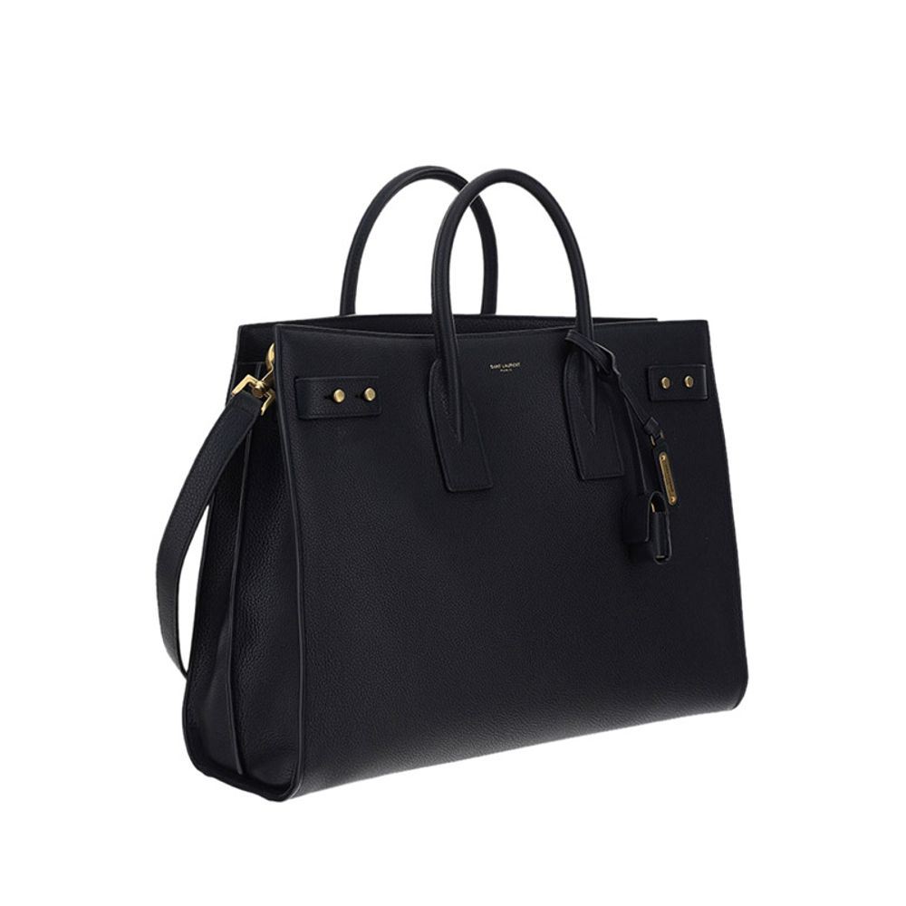 Black Calf Leather Bos Taurus HandbagThe Sac De Jour bag by Saint Laurent combines functionality and style with a soft structure, side gussets, and compression straps with tabs. It features round handles with a lock housed in a removable leather case and