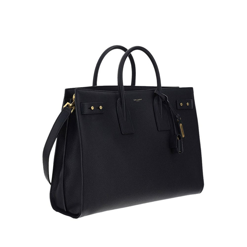 Black Calf Leather Bos Taurus HandbagThe Sac De Jour bag by Saint Laurent combines functionality and style with a soft structure, side gussets, and compression straps with tabs. It features round handles with a lock housed in a removable leather case and