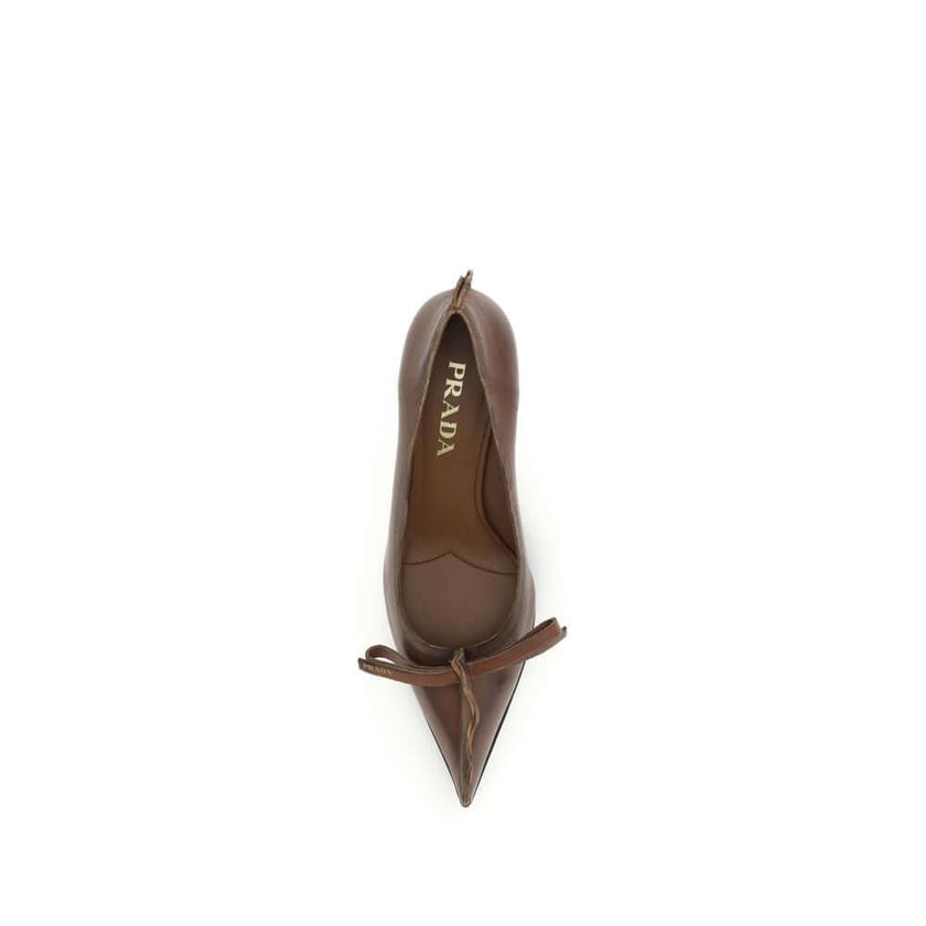 Antique leather PumpsAntique leather Pumps by Prada reinterpret a feminine classic with a bold, unconventional aesthetic. The tapered toe silhouette is crafted from leather with an antiqued effect, enhanced by exposed stitching and rough edges deliberatel