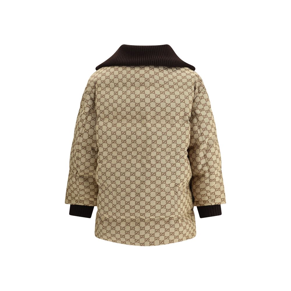 Beige Cotton BomberThe fabric Bomber Jacket by Gucci reinterprets the maison’s heritage through the GG motif in camel and ebony tones. Cut in a regular fit with dropped shoulders, the silhouette blends functionality and sophistication: a ribbed high colla