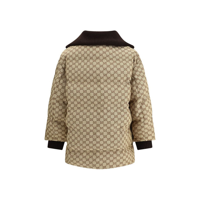 Beige Cotton BomberThe fabric Bomber Jacket by Gucci reinterprets the maison’s heritage through the GG motif in camel and ebony tones. Cut in a regular fit with dropped shoulders, the silhouette blends functionality and sophistication: a ribbed high colla