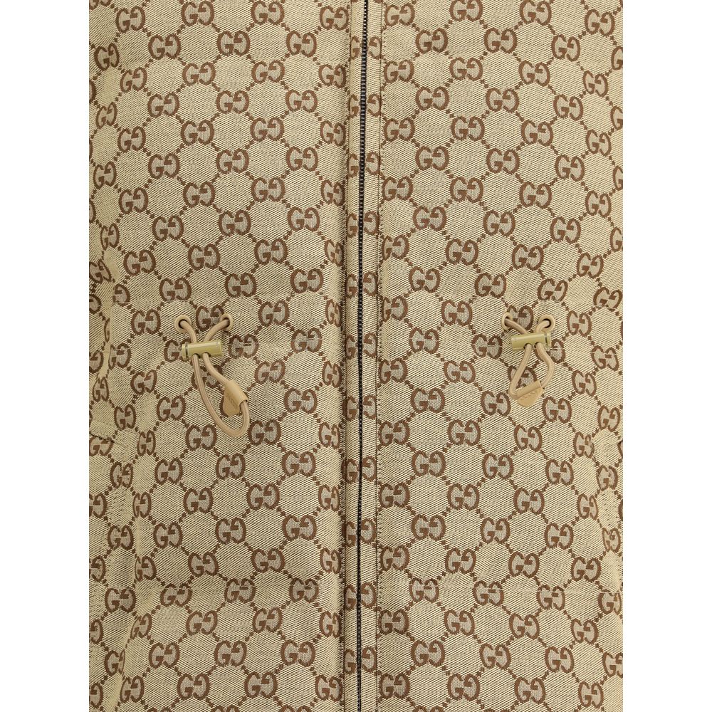 Beige Cotton BomberThe fabric Bomber Jacket by Gucci reinterprets the maison’s heritage through the GG motif in camel and ebony tones. Cut in a regular fit with dropped shoulders, the silhouette blends functionality and sophistication: a ribbed high colla
