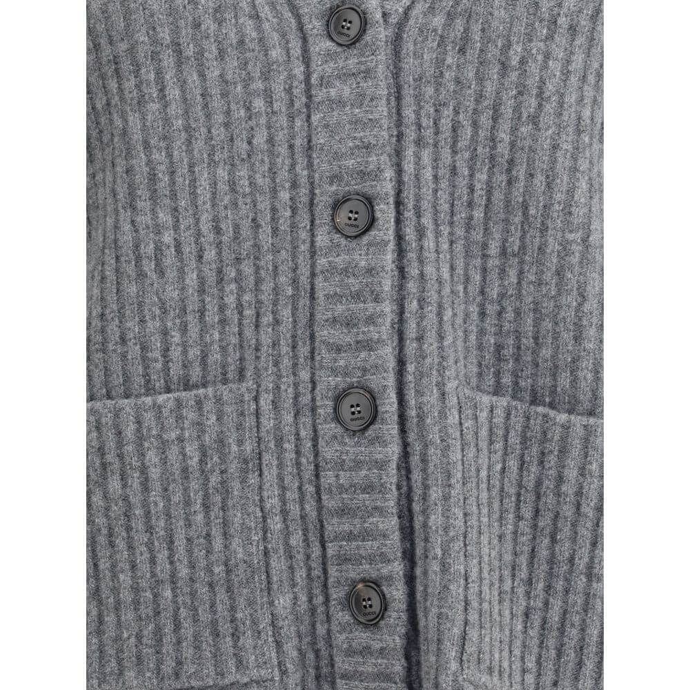 Gray Wool CardiganThe Wool Cardigan by Gucci embodies timeless elegance with its ribbed knit construction and refined V-neckline. Dropped shoulders and long sleeves create a relaxed silhouette, while the maison’s iconic green and red Web trim highlights t