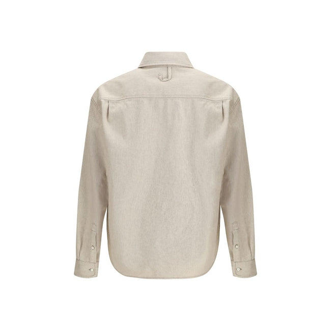 Beige Denim ShirtThe Simon denim Shirt in de-Nîmes by Jacquemus reinterprets a wardrobe classic with the Maison’s refined, contemporary spirit. Crafted from soft cotton and hemp denim, it features a straight fit that falls naturally along the body. A poin