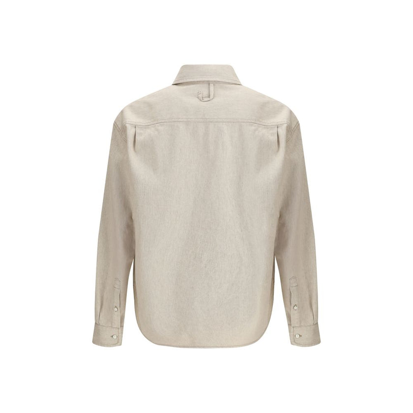 Beige Denim ShirtThe Simon denim Shirt in de-Nîmes by Jacquemus reinterprets a wardrobe classic with the Maison’s refined, contemporary spirit. Crafted from soft cotton and hemp denim, it features a straight fit that falls naturally along the body. A poin