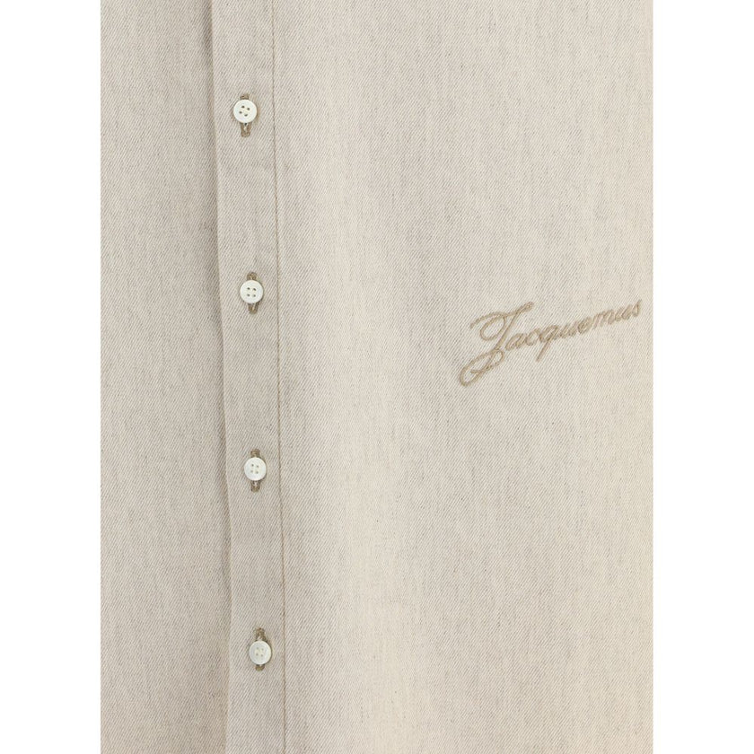 Beige Denim ShirtThe Simon denim Shirt in de-Nîmes by Jacquemus reinterprets a wardrobe classic with the Maison’s refined, contemporary spirit. Crafted from soft cotton and hemp denim, it features a straight fit that falls naturally along the body. A poin